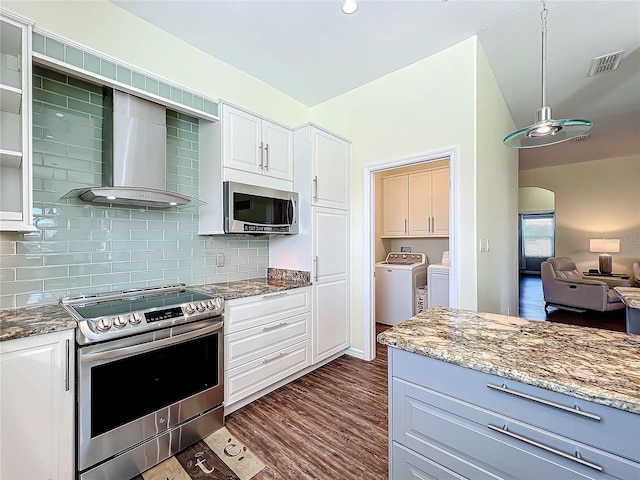 kitchen with wall chimney exhaust hood, light stone counters, washer and clothes dryer, white cabinets, and appliances with stainless steel finishes