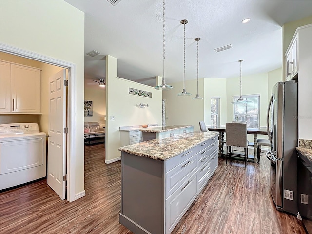 kitchen featuring a kitchen island, decorative light fixtures, white cabinets, washer / dryer, and stainless steel refrigerator