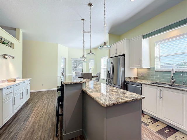 kitchen with appliances with stainless steel finishes, white cabinetry, a kitchen island, and sink