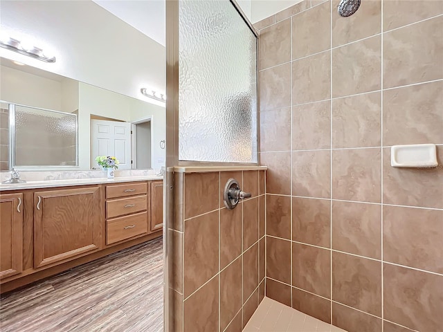 bathroom featuring tiled shower, vanity, and hardwood / wood-style flooring