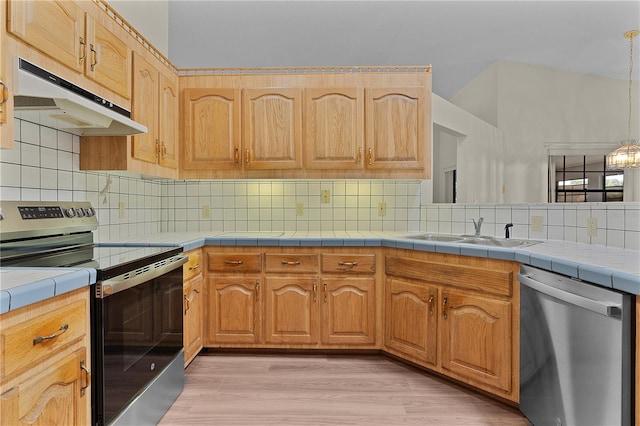 kitchen featuring tile countertops, sink, decorative backsplash, stainless steel appliances, and light hardwood / wood-style flooring