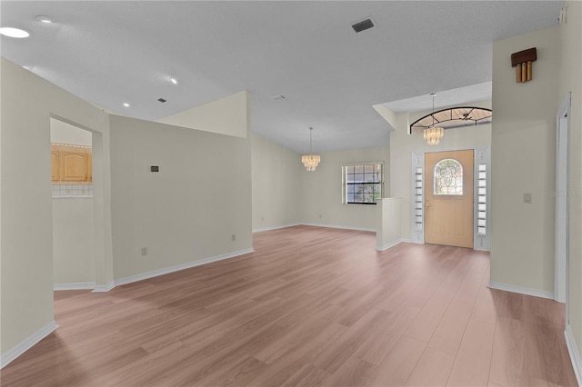 entrance foyer with a textured ceiling, an inviting chandelier, and light hardwood / wood-style floors