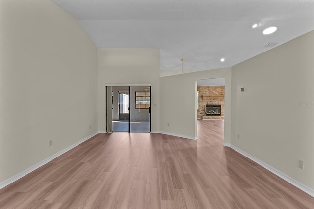 spare room featuring a large fireplace and light hardwood / wood-style flooring