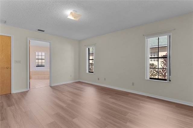 empty room with light hardwood / wood-style flooring and a textured ceiling