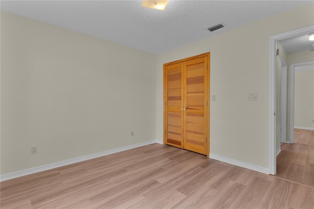 unfurnished bedroom with a closet, light hardwood / wood-style flooring, and a textured ceiling