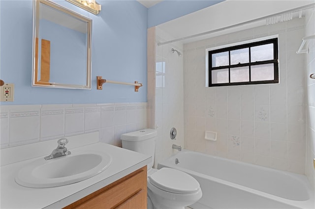 full bathroom with vanity, tiled shower / bath, tile walls, and toilet