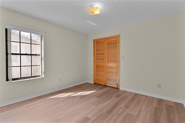 spare room with a textured ceiling and light wood-type flooring