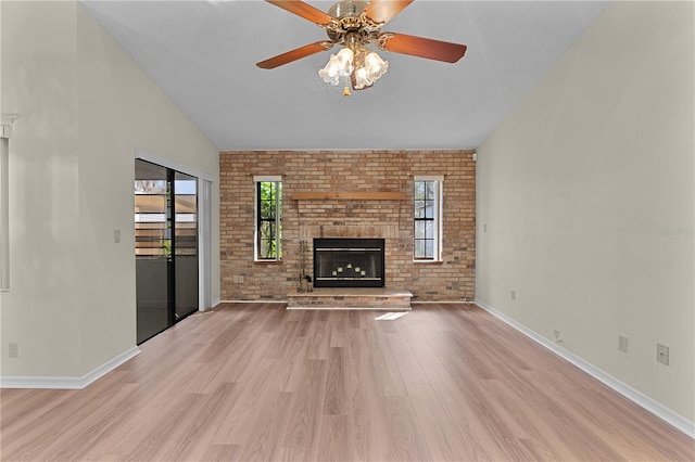 unfurnished living room with ceiling fan, brick wall, a fireplace, and light wood-type flooring