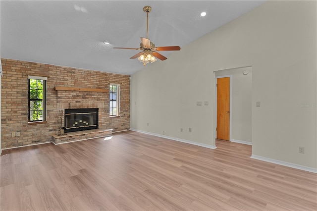 unfurnished living room with a fireplace, light hardwood / wood-style flooring, and brick wall