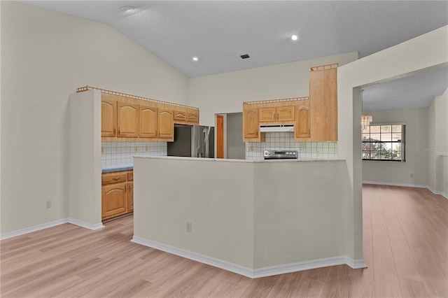 kitchen featuring appliances with stainless steel finishes, light brown cabinetry, lofted ceiling, and light hardwood / wood-style floors