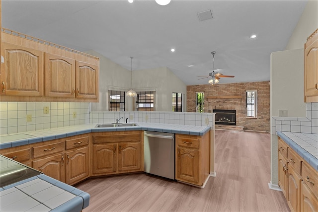 kitchen featuring tile counters, kitchen peninsula, and dishwasher