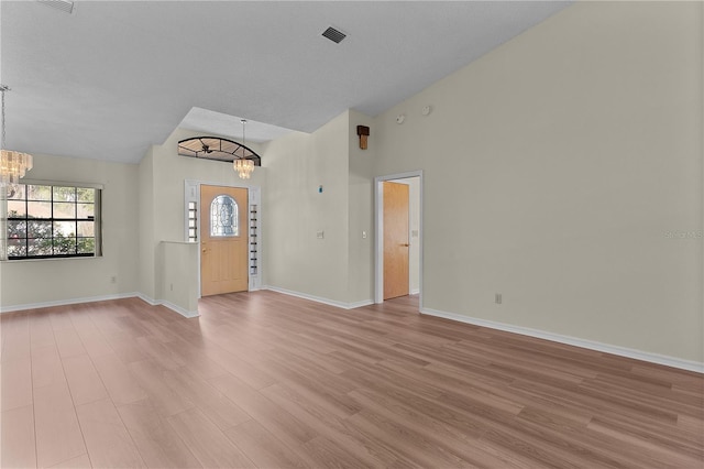 interior space featuring an inviting chandelier, high vaulted ceiling, and light hardwood / wood-style floors