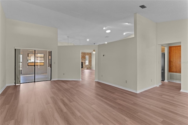 spare room with light hardwood / wood-style flooring, high vaulted ceiling, and ceiling fan