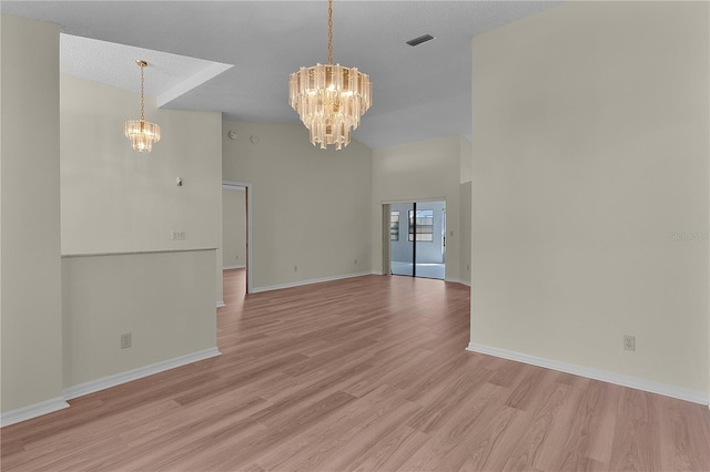 unfurnished room featuring a chandelier, high vaulted ceiling, and light wood-type flooring