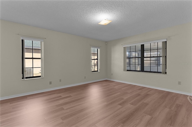 unfurnished room featuring a healthy amount of sunlight, a textured ceiling, and light hardwood / wood-style flooring