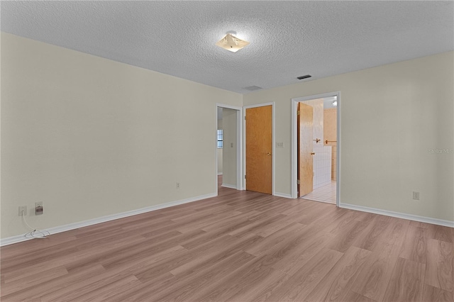 spare room with light hardwood / wood-style flooring and a textured ceiling