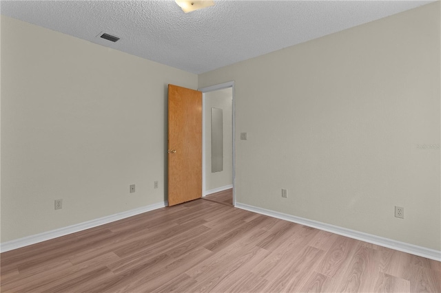 unfurnished room with light hardwood / wood-style flooring and a textured ceiling