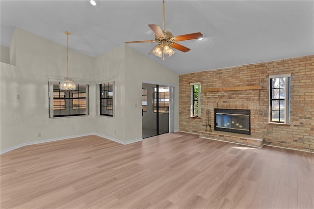 unfurnished living room with brick wall, high vaulted ceiling, a fireplace, ceiling fan, and light wood-type flooring