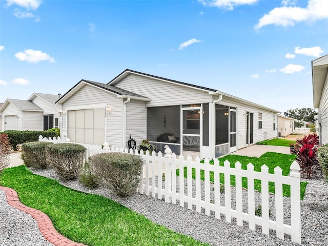 view of front of home featuring a front yard, a sunroom, and a garage