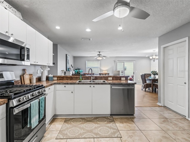 kitchen featuring white cabinetry, kitchen peninsula, stainless steel appliances, ceiling fan with notable chandelier, and sink