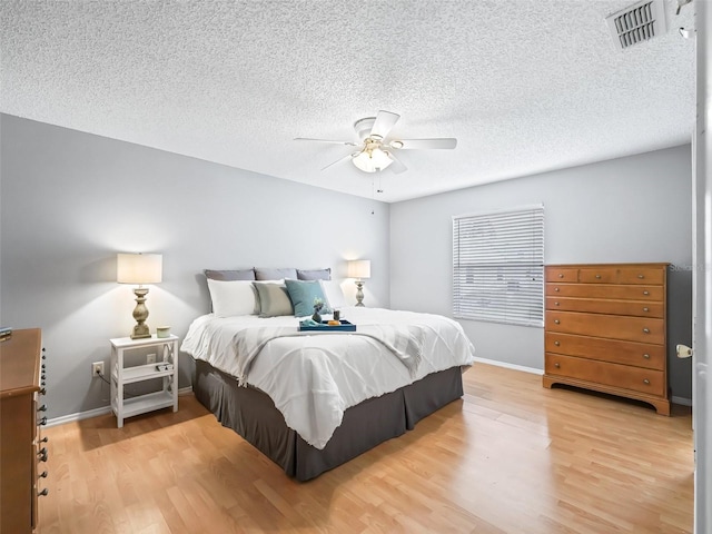 bedroom with ceiling fan, a textured ceiling, and light hardwood / wood-style flooring