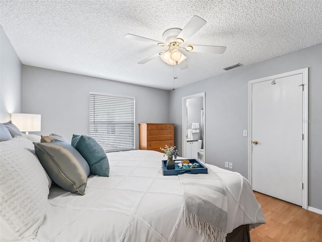 bedroom featuring a textured ceiling, ceiling fan, ensuite bathroom, and hardwood / wood-style floors