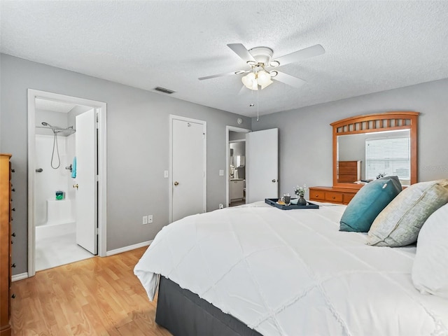 bedroom with ceiling fan, a textured ceiling, connected bathroom, and light hardwood / wood-style floors