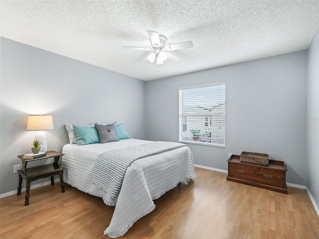 bedroom with ceiling fan, a textured ceiling, and light hardwood / wood-style floors