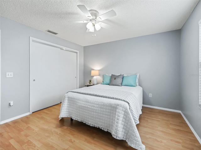 bedroom with light wood-type flooring, a closet, a textured ceiling, and ceiling fan