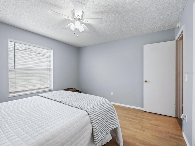 bedroom featuring ceiling fan, a textured ceiling, and light hardwood / wood-style flooring