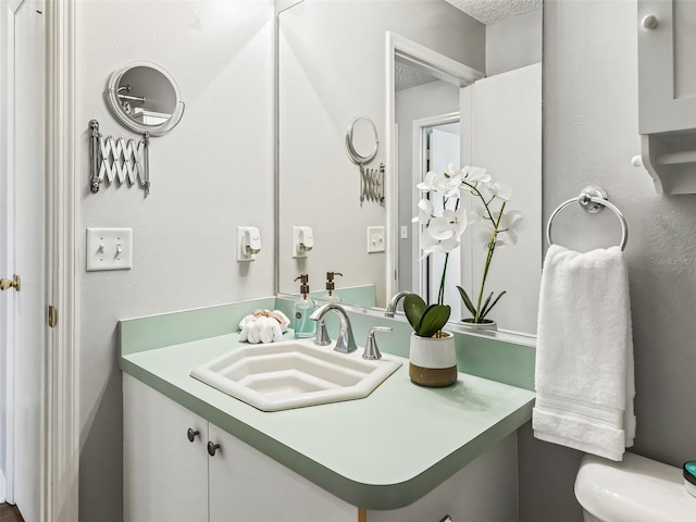 bathroom featuring a textured ceiling, toilet, and vanity