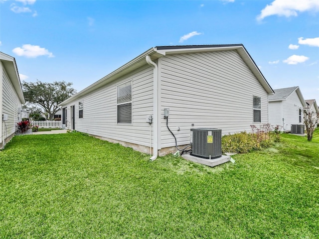 view of side of home with central AC and a lawn