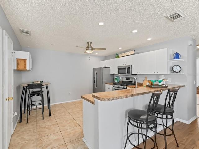 kitchen featuring ceiling fan, white cabinetry, appliances with stainless steel finishes, and kitchen peninsula