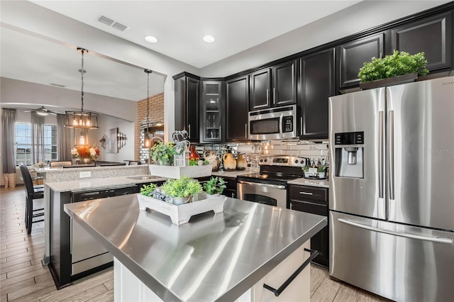 kitchen with pendant lighting, a center island, a kitchen breakfast bar, appliances with stainless steel finishes, and kitchen peninsula