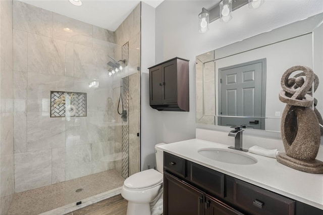 bathroom featuring vanity, toilet, wood-type flooring, and a tile shower