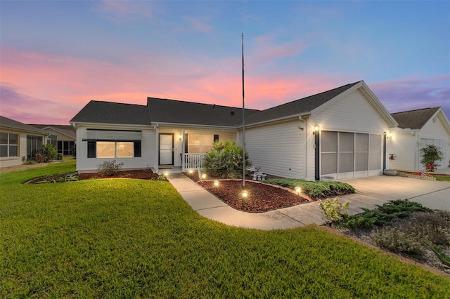 ranch-style house with a porch, a yard, and a garage