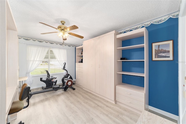 workout room with ceiling fan, light wood-type flooring, a textured ceiling, and built in shelves