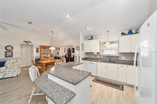 kitchen featuring pendant lighting, white appliances, white cabinetry, and a kitchen island