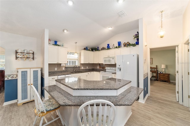 kitchen featuring a breakfast bar, sink, hanging light fixtures, and white appliances