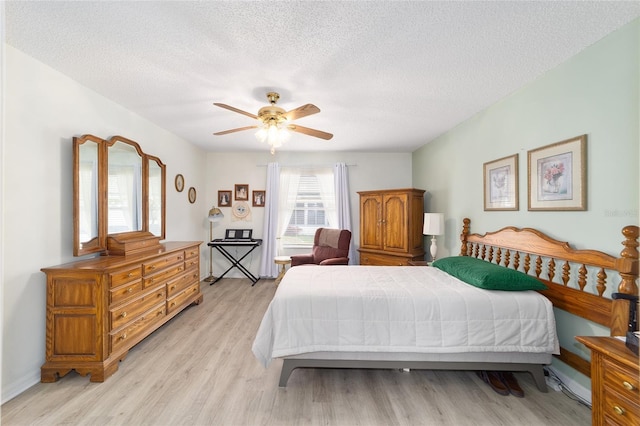 bedroom featuring ceiling fan, light hardwood / wood-style floors, and a textured ceiling