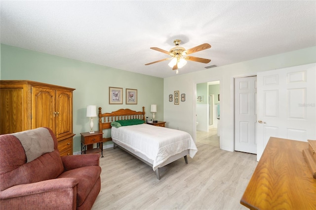 bedroom with ceiling fan, light hardwood / wood-style floors, and a textured ceiling