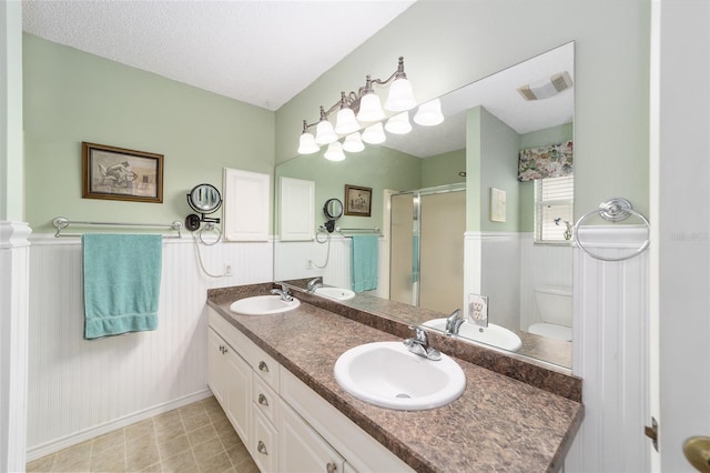 bathroom featuring vanity, toilet, an enclosed shower, and a textured ceiling