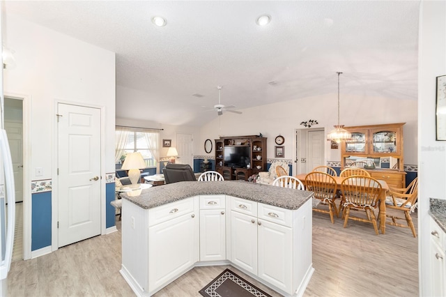 kitchen featuring ceiling fan, light hardwood / wood-style flooring, white cabinets, hanging light fixtures, and lofted ceiling