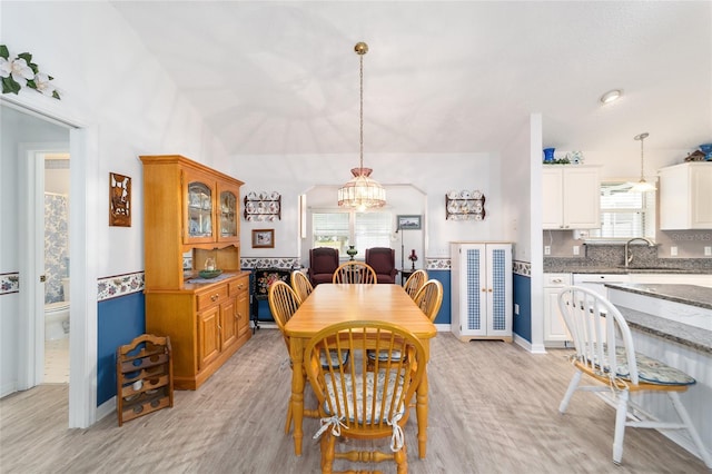 dining area featuring a notable chandelier, light hardwood / wood-style floors, and sink