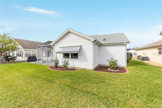 rear view of property with central AC and a lawn