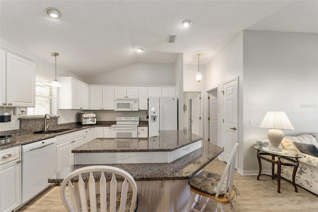 1904 De Hoyos Pl, The Villages, FL 32159 - kitchen with white appliances, a kitchen breakfast bar, white cabinetry, a center island, and a sink