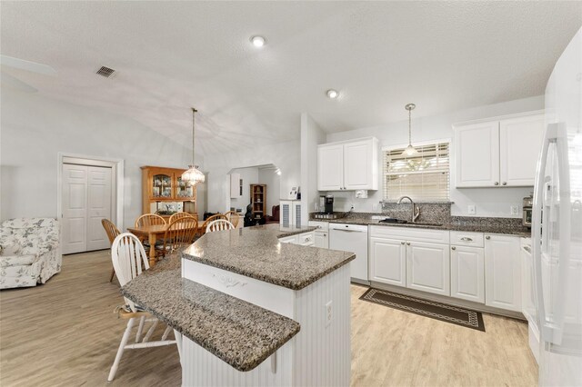 1904 De Hoyos Pl, The Villages, FL 32159 - kitchen with white appliances, vaulted ceiling, a kitchen island, a sink, and light wood finished floors