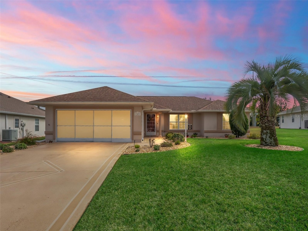 ranch-style house with a garage, a yard, and central air condition unit