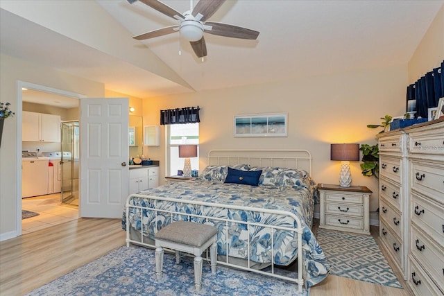 bedroom featuring lofted ceiling, ensuite bath, washer and clothes dryer, ceiling fan, and light hardwood / wood-style floors