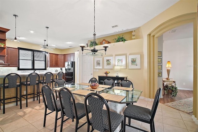 dining space featuring light tile patterned flooring and ceiling fan with notable chandelier